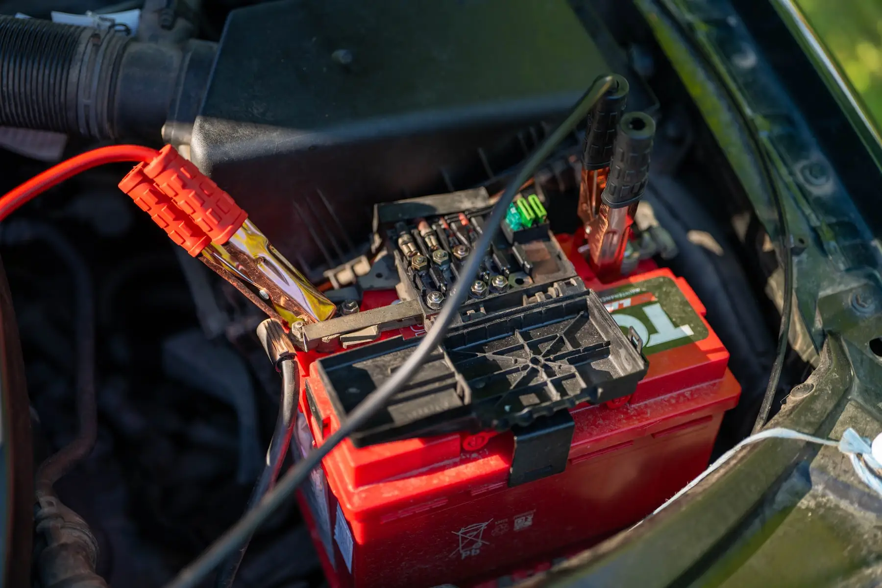 A car battery in an engine bay with the terminal clamp removed